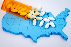 White pharmaceutical pills spilling from prescription bottle over American map