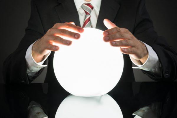 Close-up Of Businessman Predicting Future With Crystal Ball At Desk