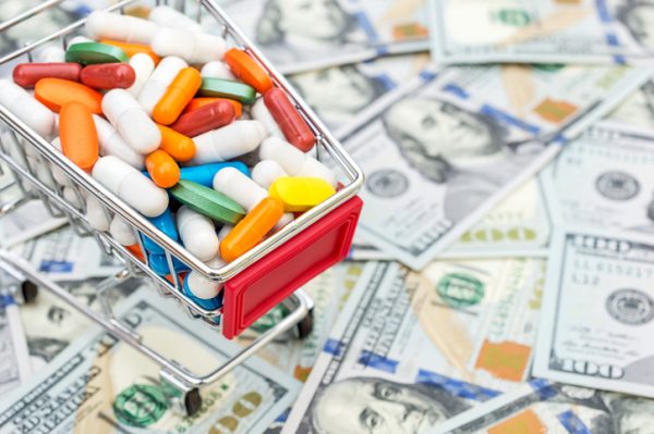 Full shopping cart with pills on background of dollar bills. Close up. Space for text.