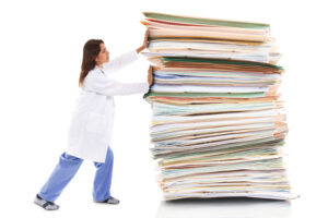 A female healthcare worker pushing a giant stack of papers isolated on a white background showing burnout