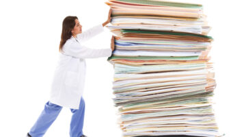 A female healthcare worker pushing a giant stack of papers isolated on a white background showing burnout