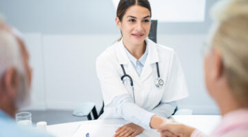 Young female doctor shaking hands with senior couple.