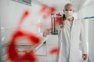 A doctor wearing a mask with a gun pointing straight and a bloody handprint workplace violence