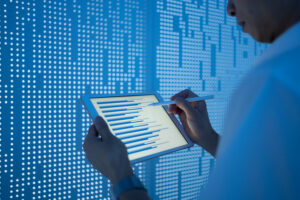 Asian man using tablet in front of a blue screen of data