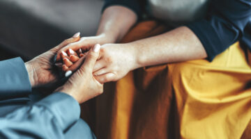 Two women sitting in armchairs. Woman psychologist talking to patient woman. Coach giving hands to smiling woman. Therapist's gestures.