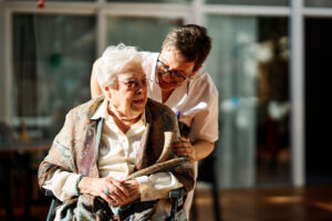 Nursing assistant taking care of senior woman in wheelchair in a nursing home