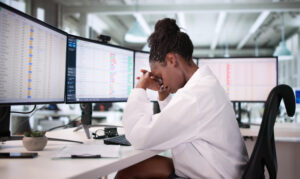 A frustrated hospital nurse struggles with data spreadsheets on a computer screen