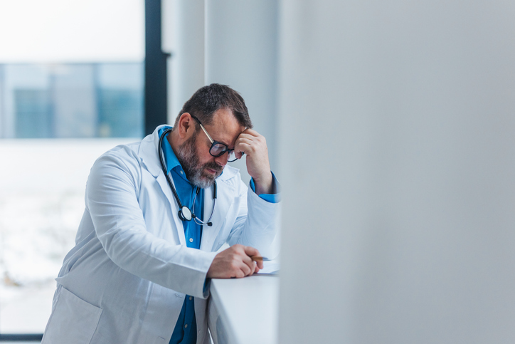 Doctor feeling overwhelmed at work, feeling exhausted, writing notes in clipboard. Healthcare workers having stressful job. Burnout syndrome for doctors and nurses.