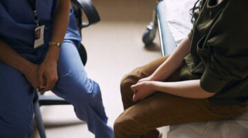 High angle view of doctor with patient sitting on examination table in clinic