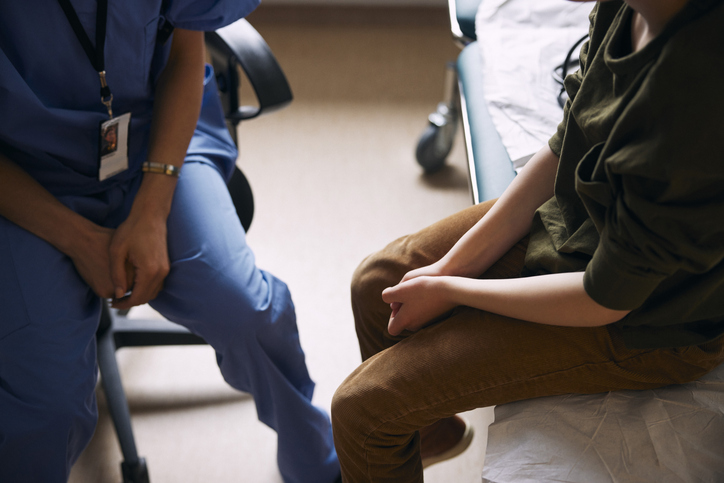 High angle view of doctor with patient sitting on examination table in clinic