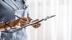 Female doctor filling up medical form on clipboard closeup. Healthcare, insurance and medicine concept.