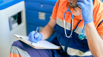 doctor writing on a clipboard while talking on the phone