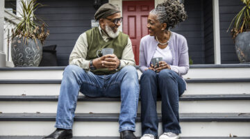 Senior couple having coffee in front of suburban home
