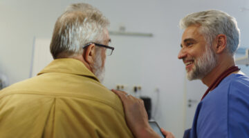Doctor comforting older male patient, talking with him.
