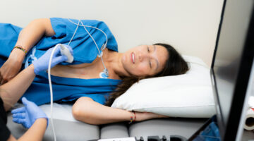 Female patient undergoing heart ultrasound with medical technician performing diagnostic procedure in hospital environment