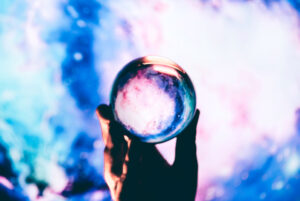 Hand holding a crystal ball with a mesmerizing swirl of cosmic colors inside, creating a portal-like view to an otherworldly galaxy. The beauty of the universe, a reflective wonder. Intergalactic journey