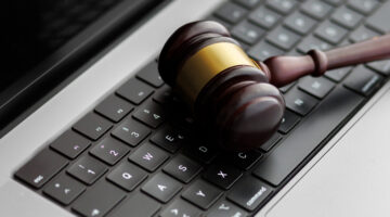 A wooden judge’s gavel lying on a laptop keyboard symbolizes online law, digital justice, and modern legal decisions in cyberspace.