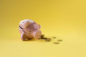 Broken fallen piggy bank with coins scattered around.
