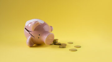 Broken fallen piggy bank with coins scattered around.