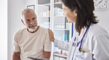 Female medical expert consoling senior patient. Senior man getting test results from doctor. They are sitting in examination room.