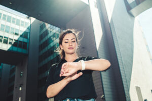 Businesswoman using smartwatch in a city.