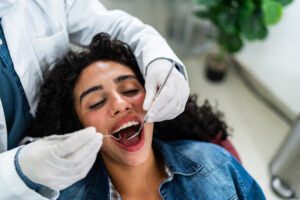 Dentist examining young patient woman teeth at dentist's office