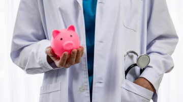 Doctor holding piggy bank in financial insurance concept in hospital