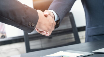 Good deal. Close-up of two business people shaking hands while sitting at the working place