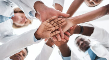 Closeup shot of a group of medical practitioners joining their hands together in a huddle